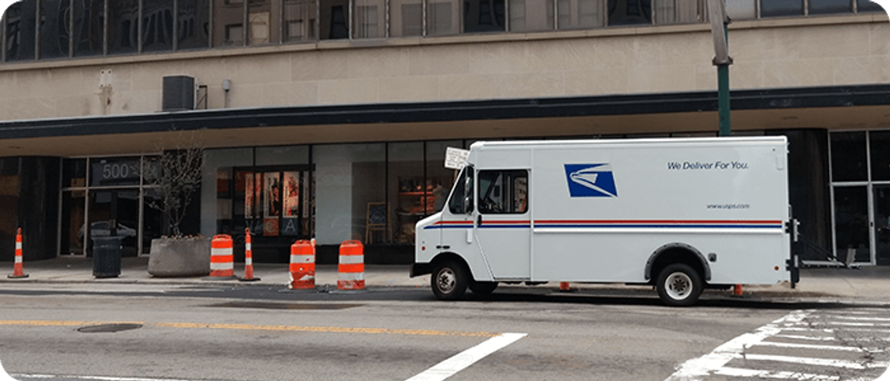 A photo of a UPS mail truck parked outside of a building.