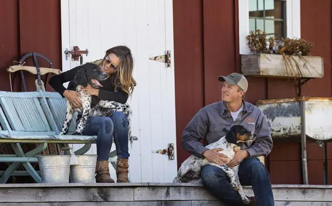 Man and woman sitting on porch with two setter puppies