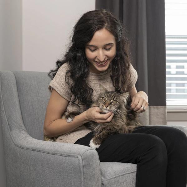 Woman sitting in chair, petting cat in lap