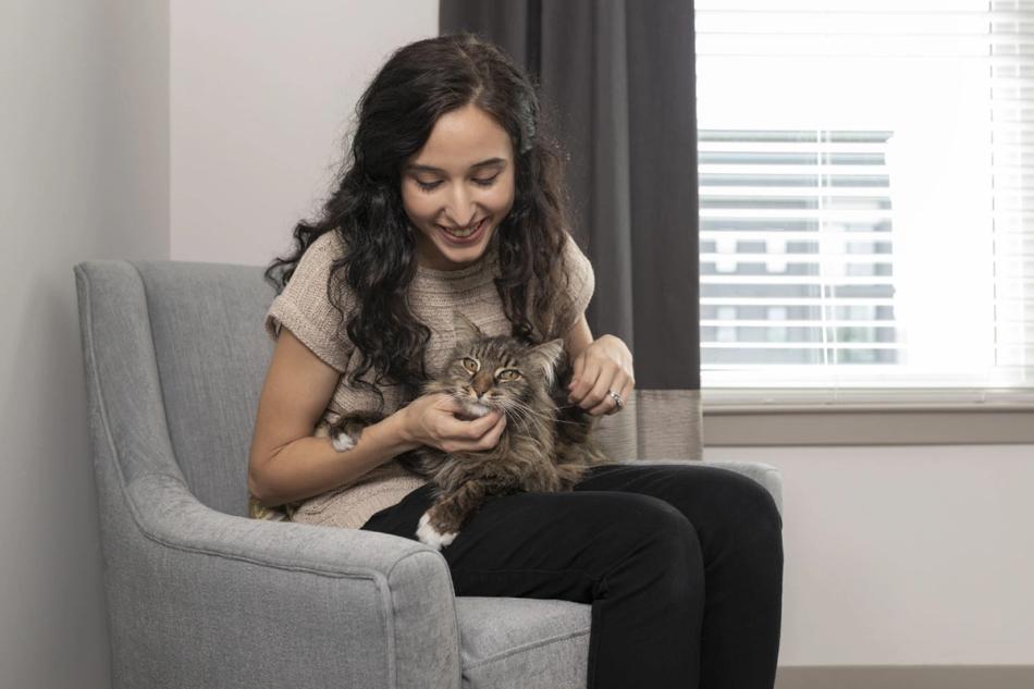 Woman sitting in chair, petting cat in lap