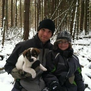 Stephen and his son pose with Cody on a winter hike.