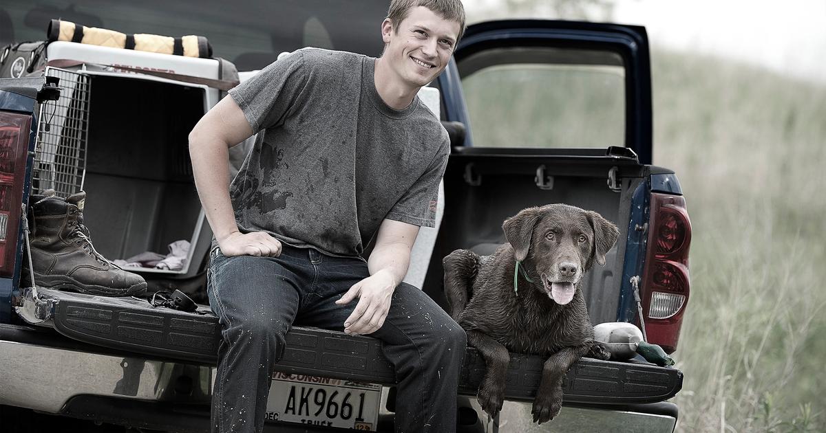 Man and chocolate lab sitting on the back of a ute