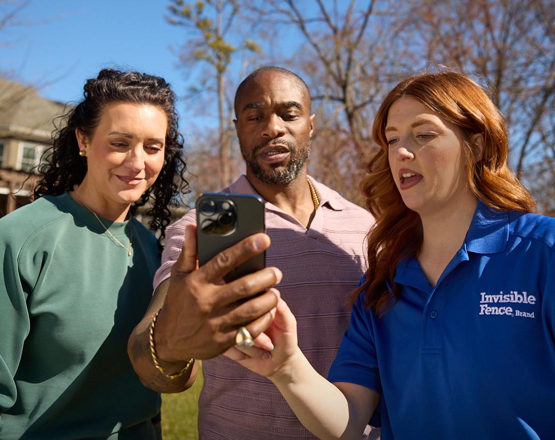 Pet trainer guiding man and woman through mobile app setup