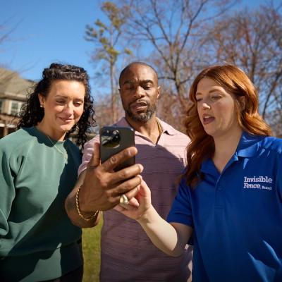 Pet trainer guiding man and woman through app setup on phone