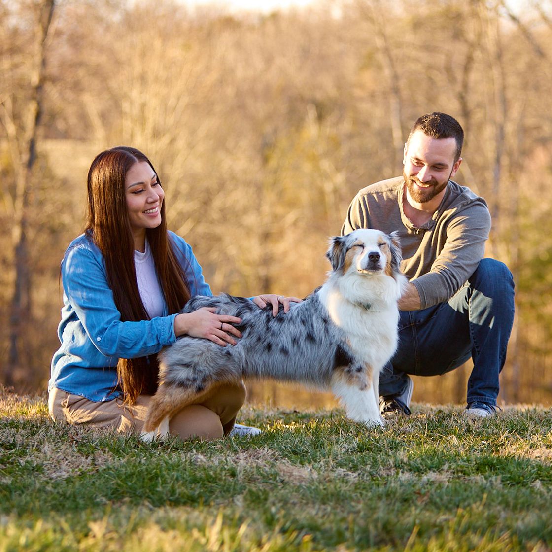 woman and man petting dog outside
