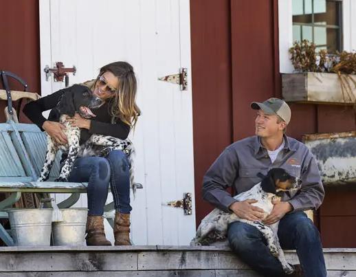 Man and woman sitting on porch with two setter puppies