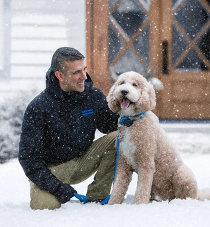 invisible fence trainer works with a poodle in a snowy yard