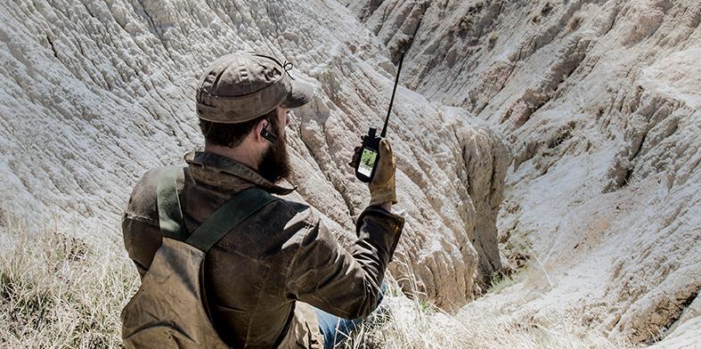 homme assis dans une vaste étendue sauvage regardant l'écran du TEK 2.0 portable