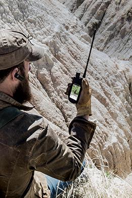 man sitting in vast wilderness looking at TEK 2.0 handheld screen