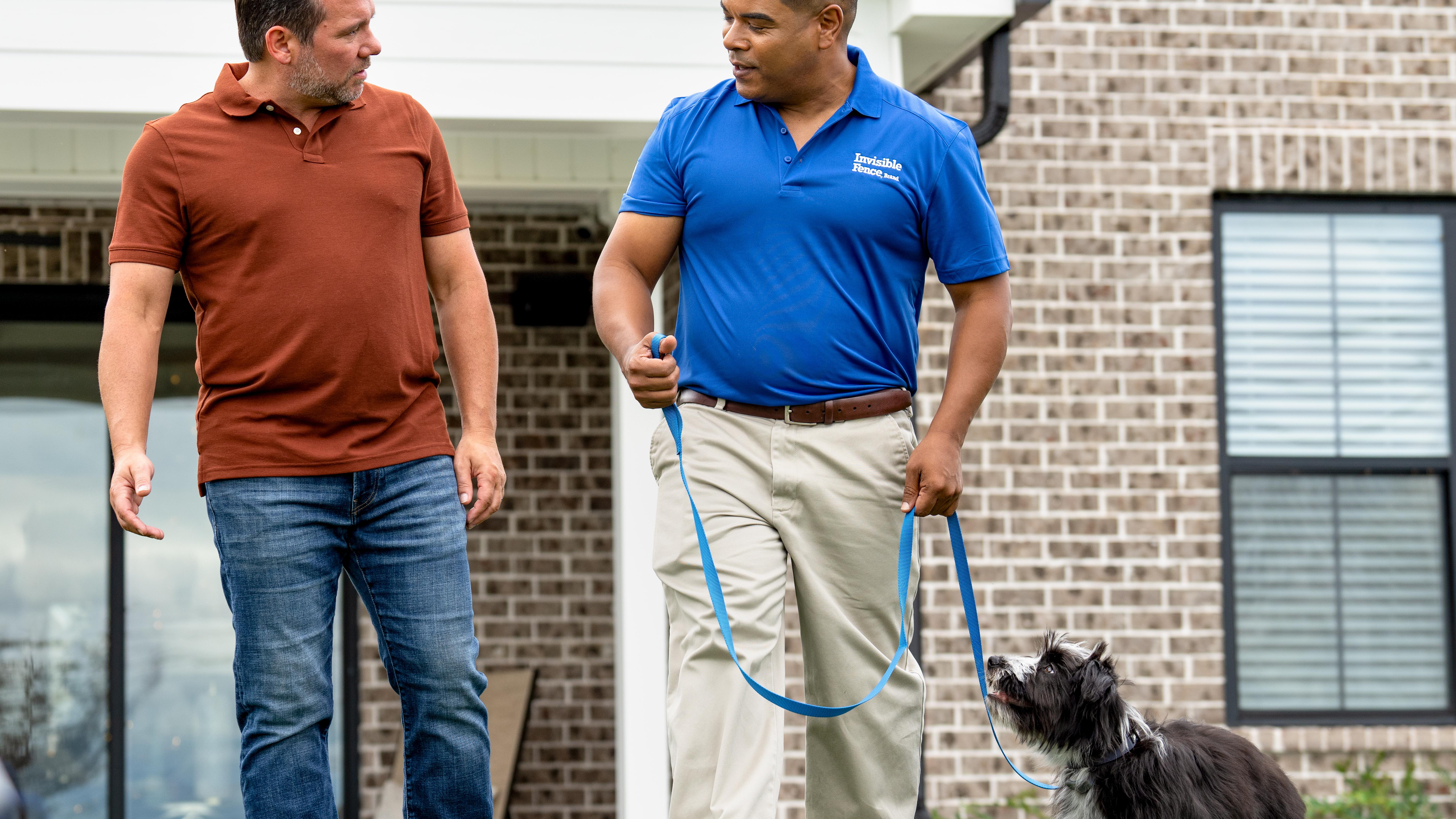invisible fence trainer walks puppy on a leash with its owner