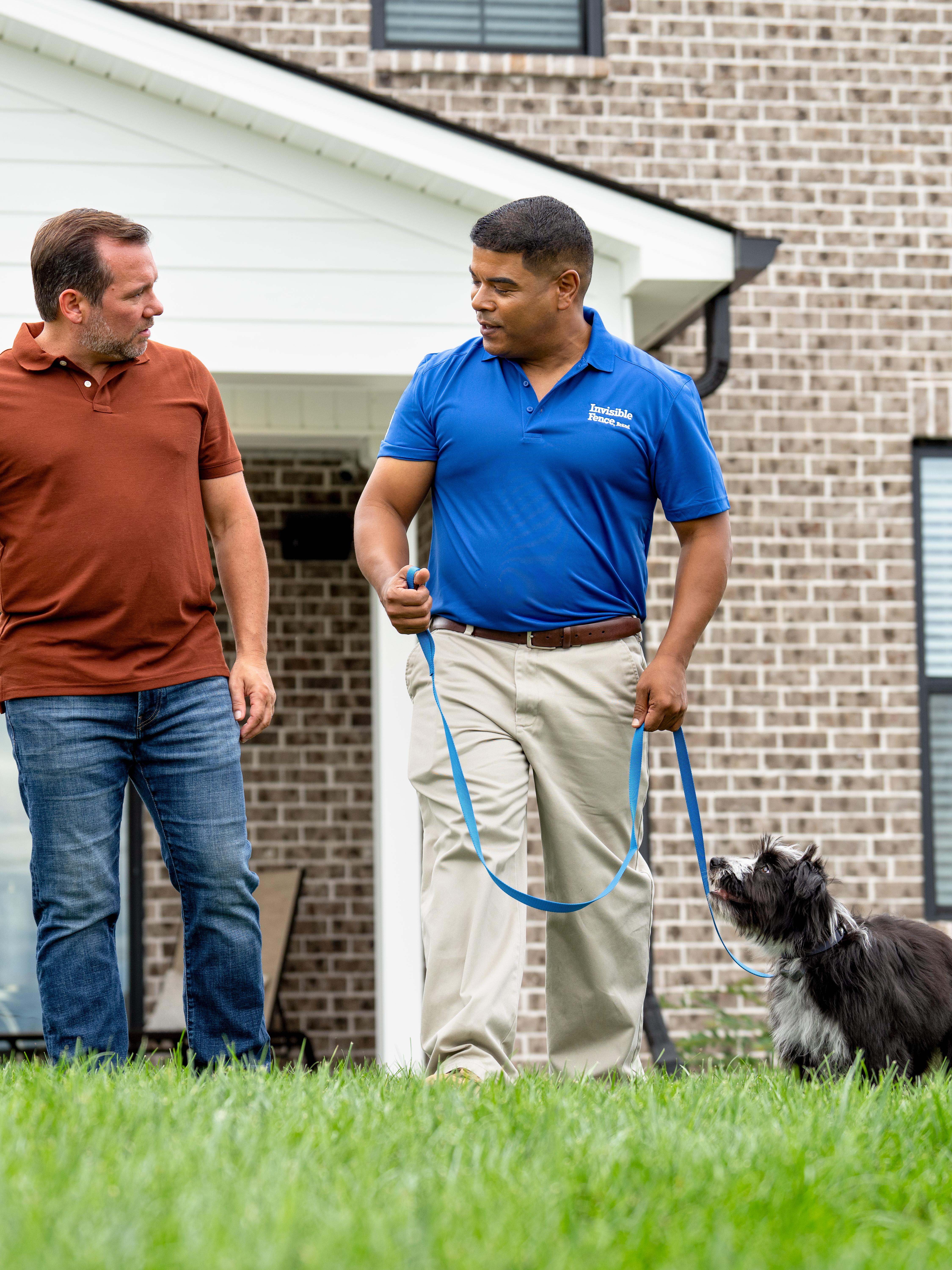 invisible fence trainer walks puppy on a leash with its owner