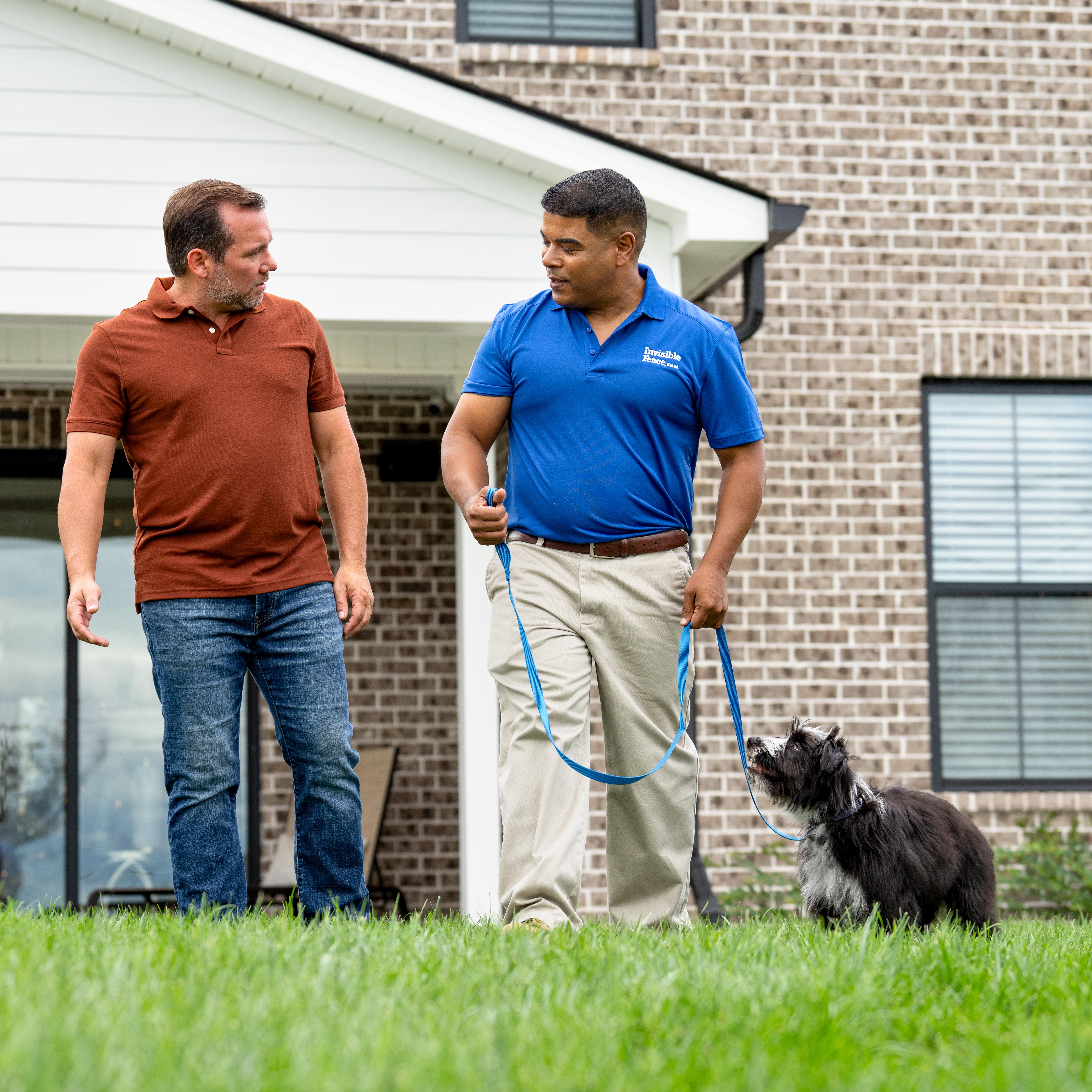 invisible fence trainer walks puppy on a leash with its owner