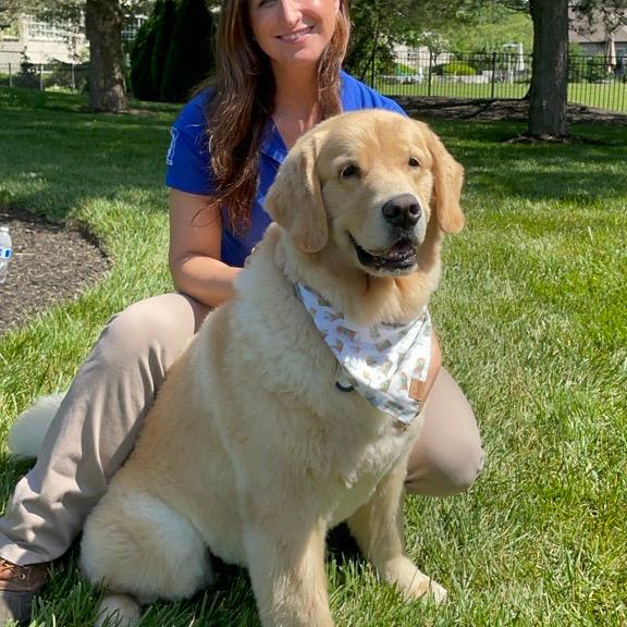 Ashley poses in the yard with a dog she has trained on an invisible fence system