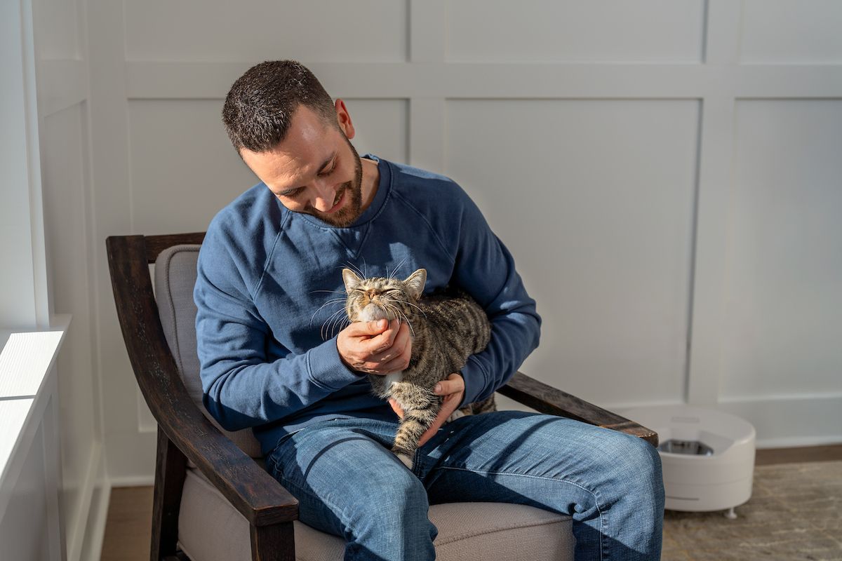 Man siting in chair petting cat