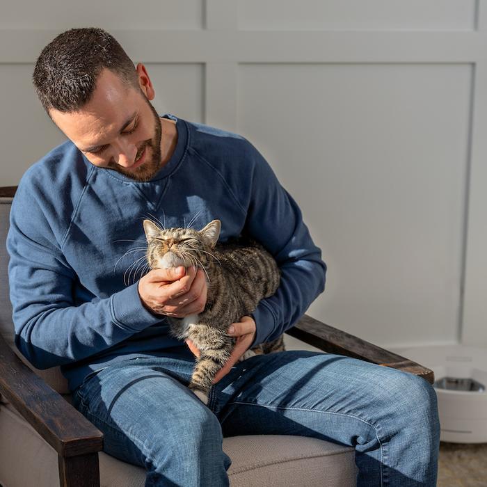 Man siting in chair petting cat