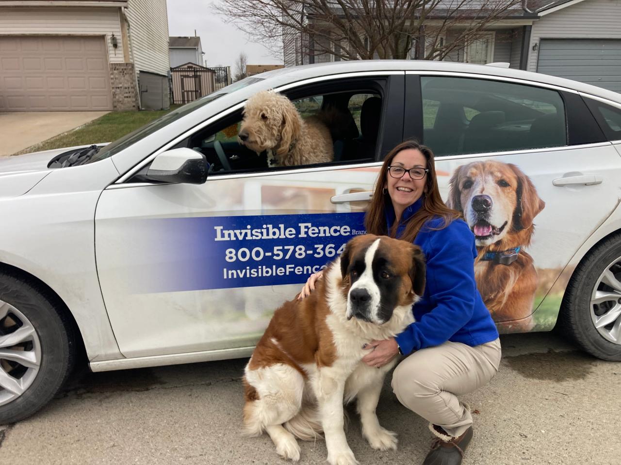invisible fence trainer posing with dogs in front of car