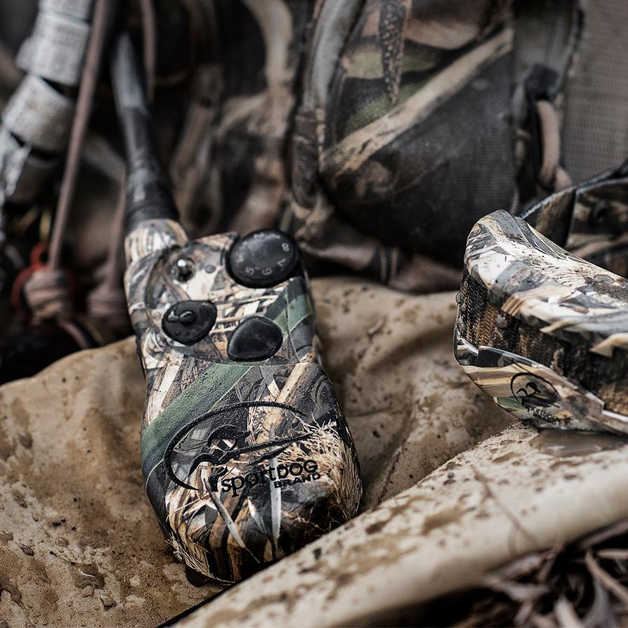 pile of waterfowl gear with focus on camouflaged e-collar system