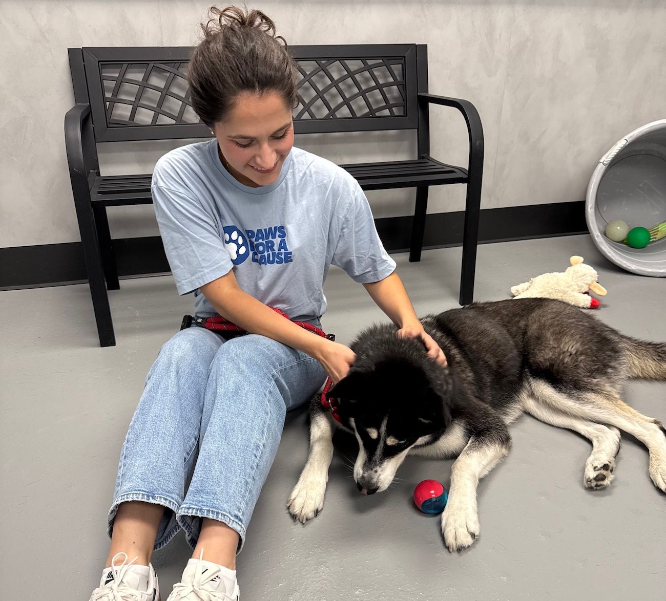 Woman sitting in floor with Husky mix dog at a pet shelter
