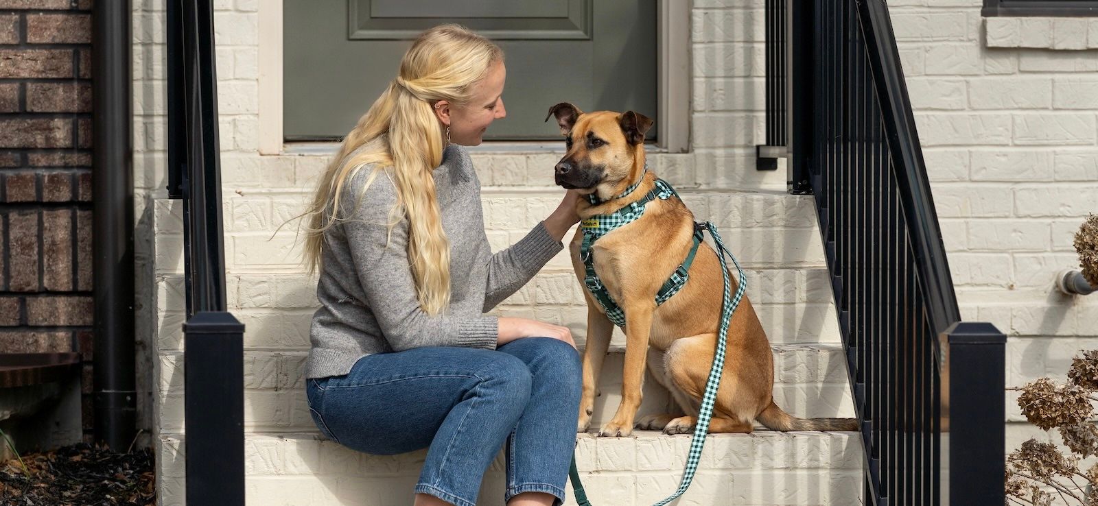 Woman sitting on stoop petting her dog