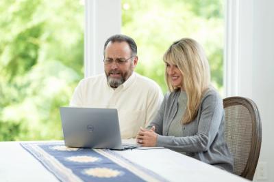 man and woman sit at table on laptop