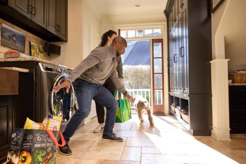 dog bolting out open door in kitchen while couple brings in groceries