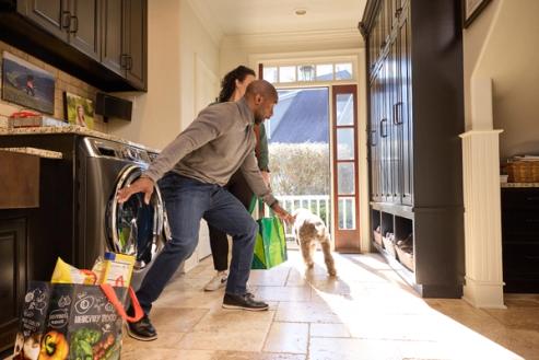dog bolting out open door in kitchen while couple brings in groceries