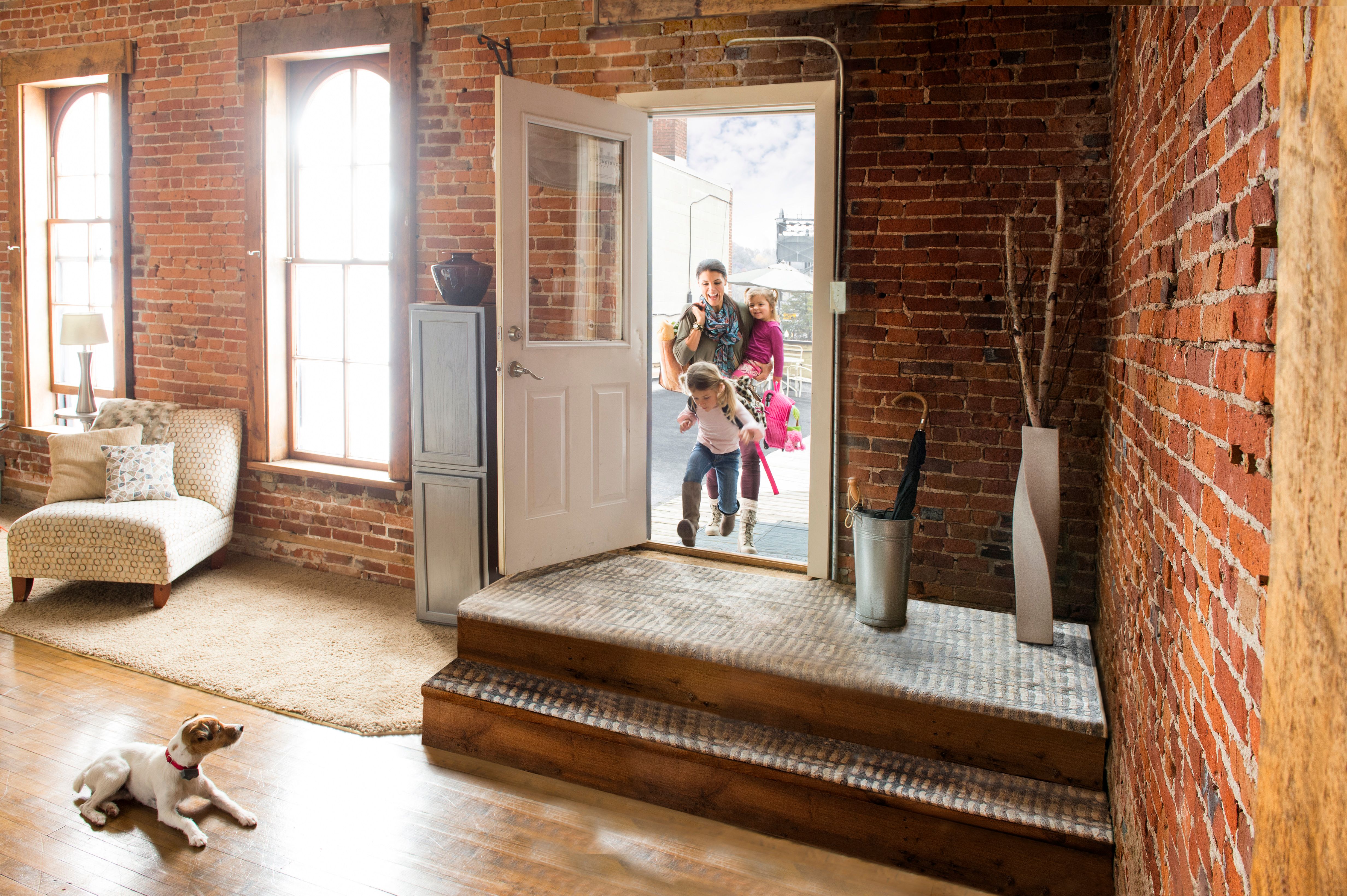 relaxed homeowner opening front door with dog calmly staying back