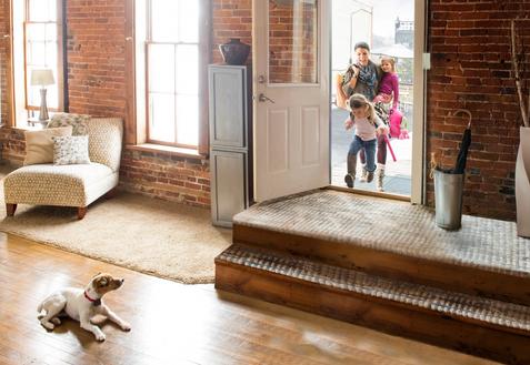 relaxed homeowner opening front door with dog calmly staying back