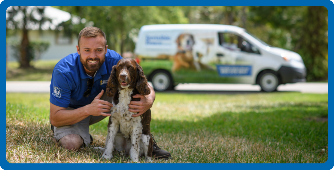 Invisible Fence trainer smiling and sitting with dog in front of Invisible Fence Brand van