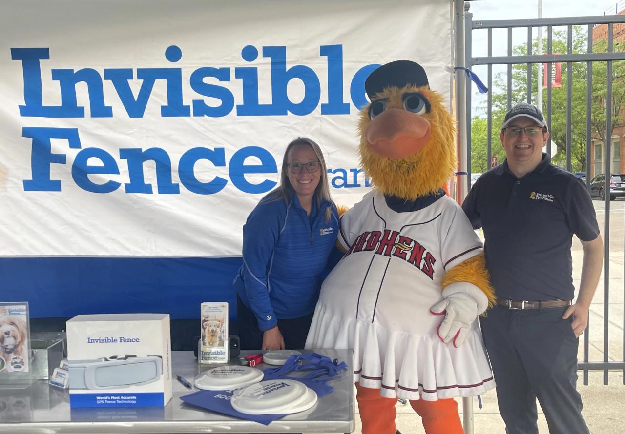 invisible fence of northwest ohio teammates in booth with team mascot at local baseball event 