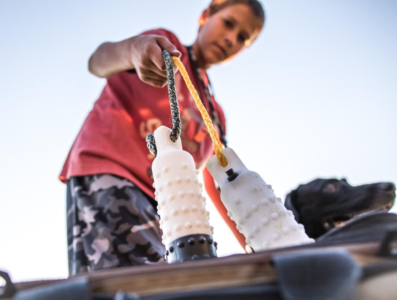 Jeune garçon retirant des mannequins d'un sac d'équipement avec un labrador noir à ses côtés.