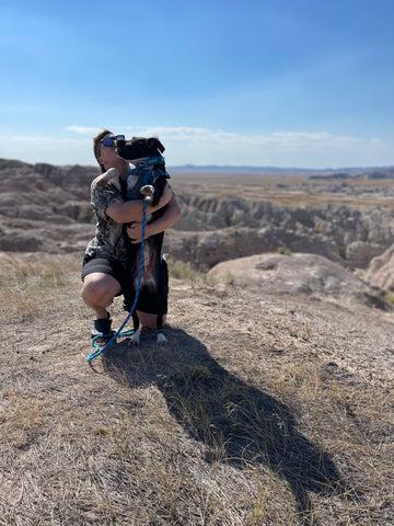 Jenny's partner Brie (they/them) poses with Judy (she/her) on a sunny, mountain trail.