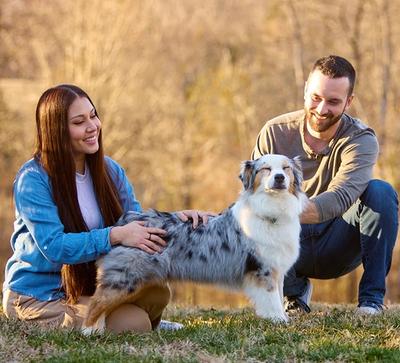 woman and man petting dog outside