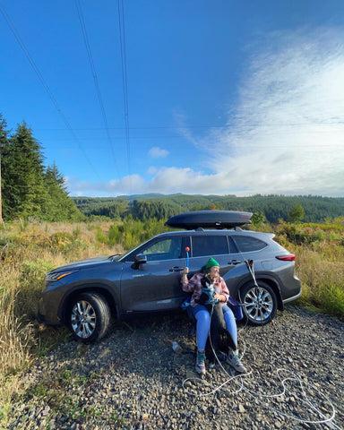 Jenny and Big Judy sit outside their parked SUV. It is a bright, sunny, Fall day.