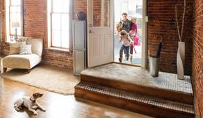 small dog sitting by door as family walks through the door