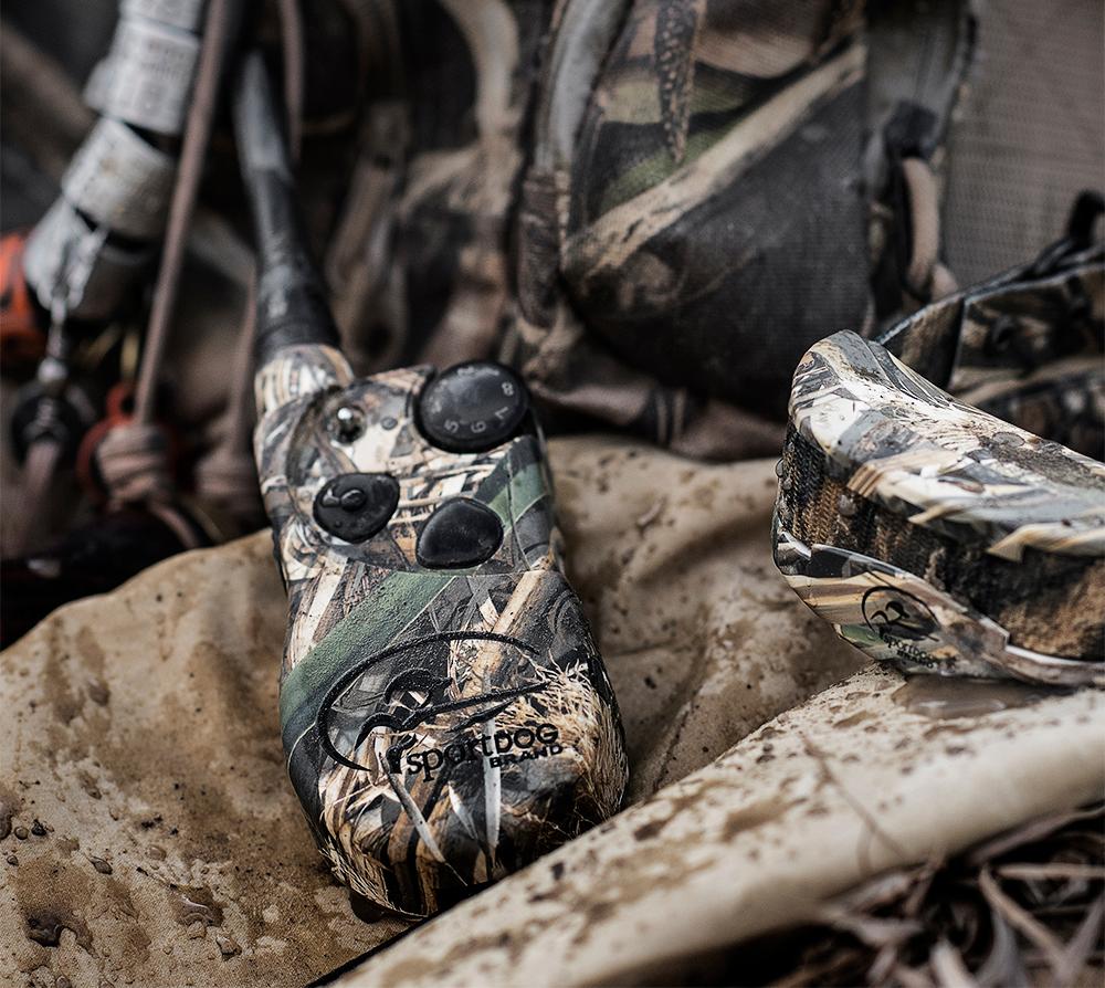 pile of waterfowl gear with focus on camouflaged e-collar system