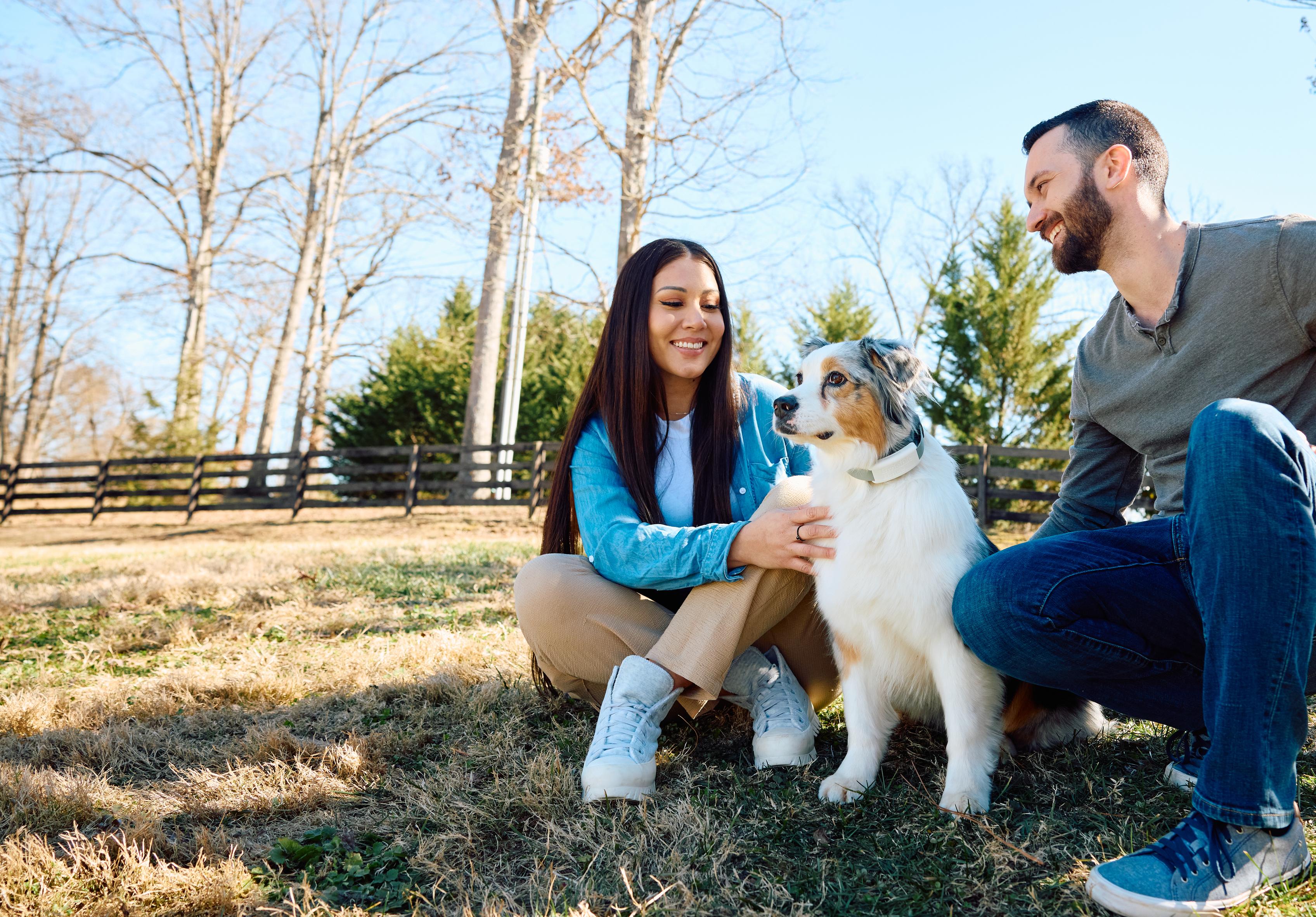 Husband and wife enjoying outdoors with their dog off-leash