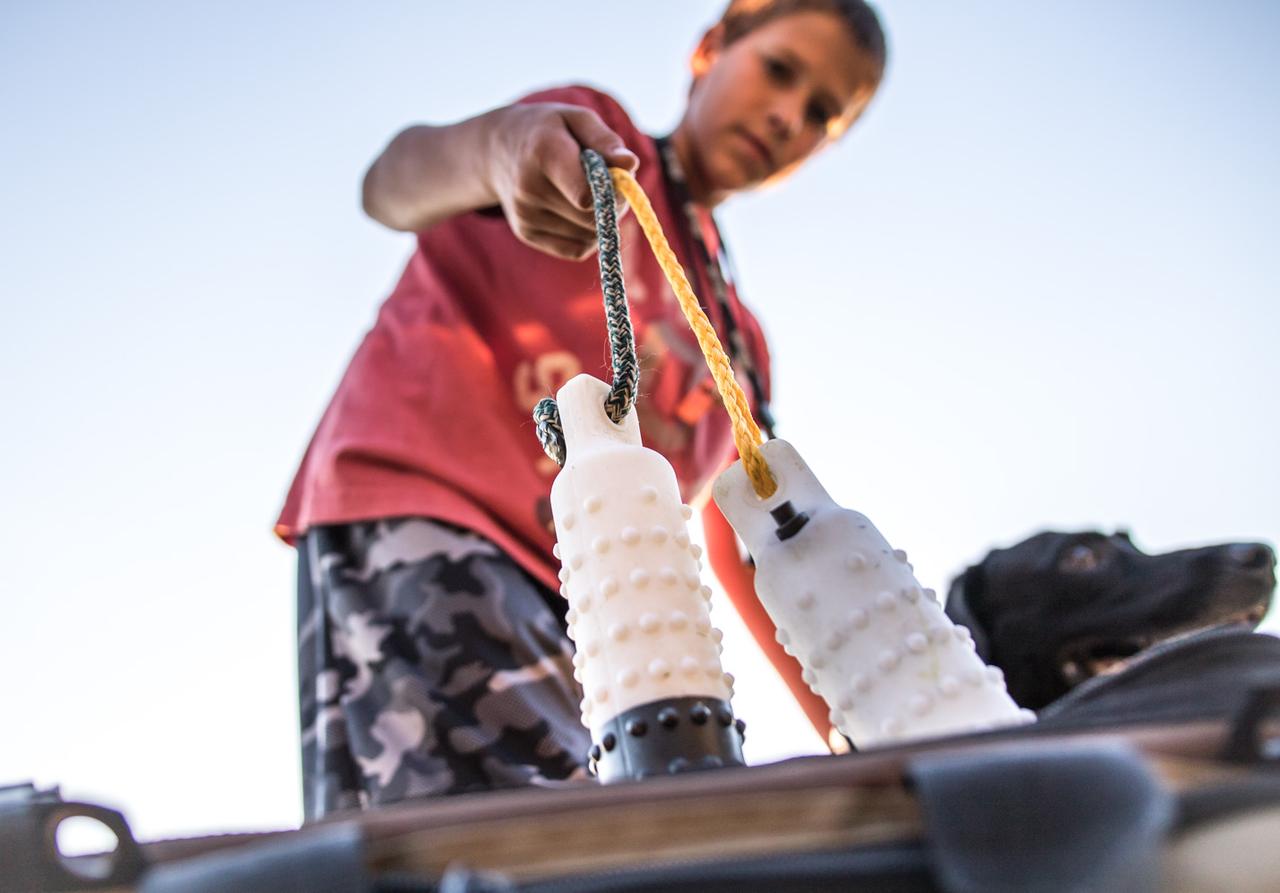 Young boy pulling dummies out of gear back with black lab at side.