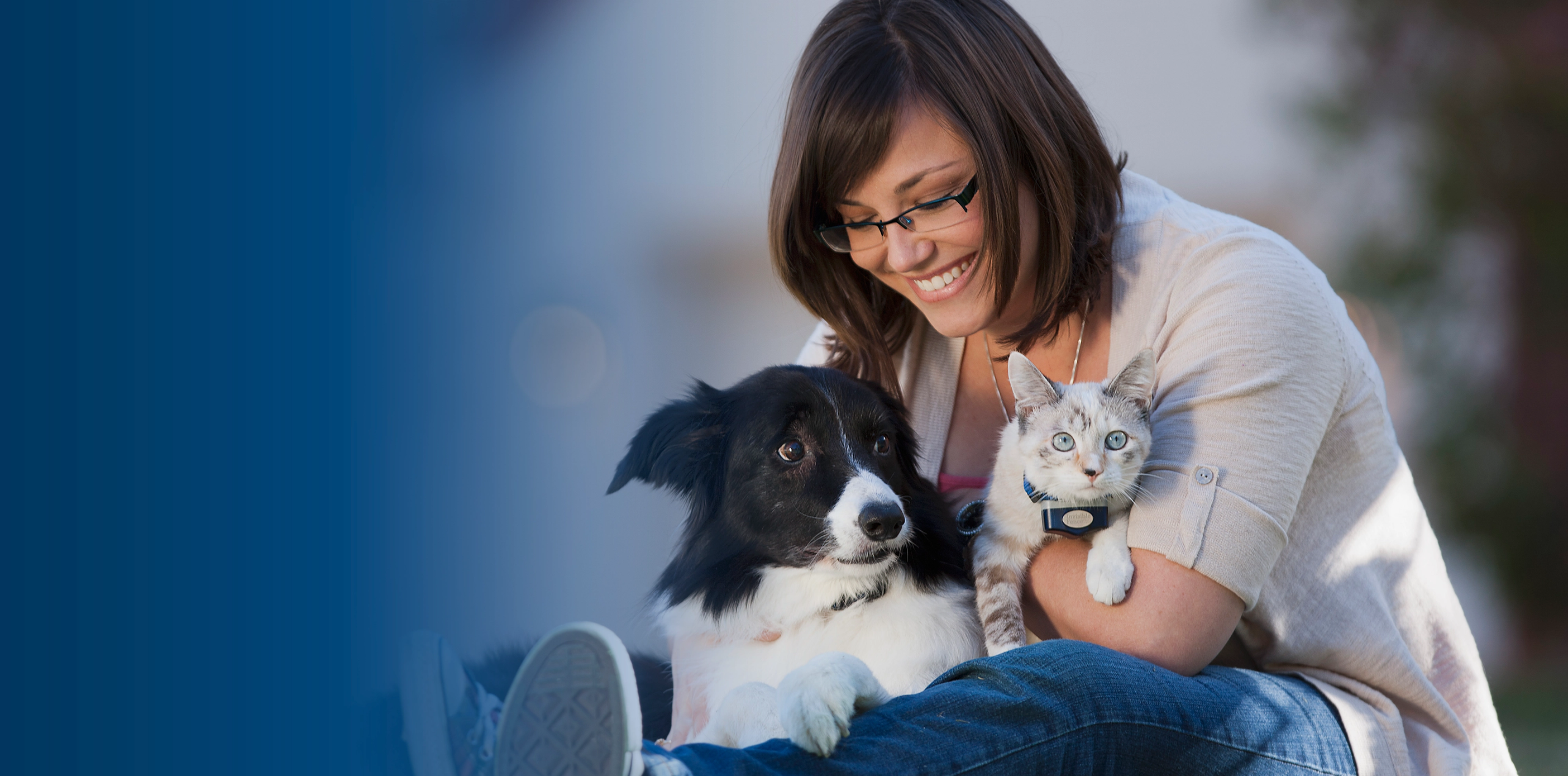 Woman hugging her dog and cat who are wearing Invisible Fence collars.