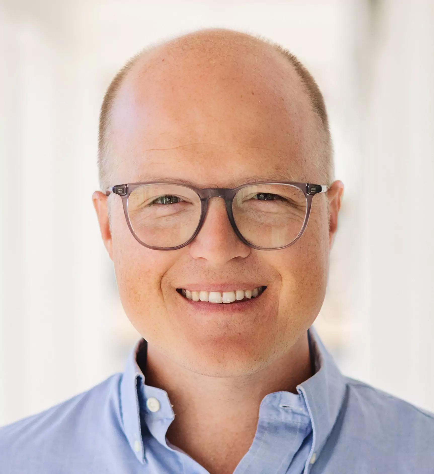 Sebastian Brenner, co-founder of METYCLE; person wearing a light blue button-down shirt with a white background, smiling and looking directly at the camera, wearing glasses