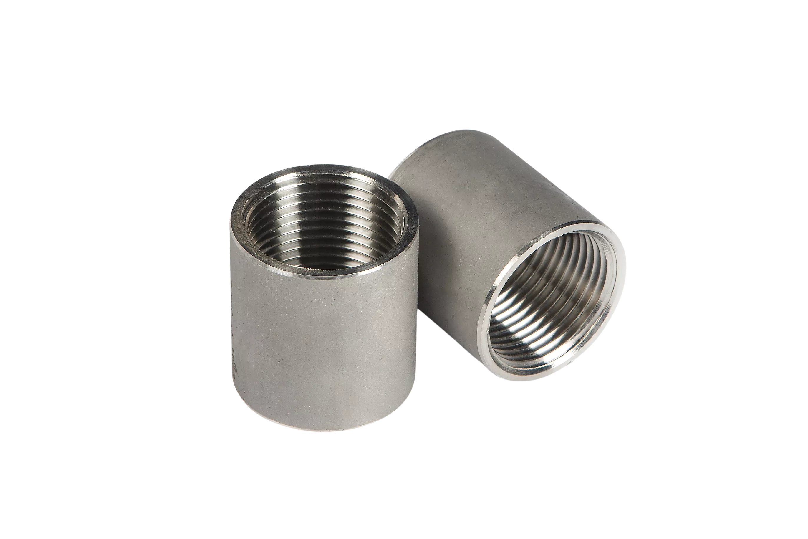Two cylindrical metal pipe fittings, both with internal threading. The fittings are made of a shiny, silver-colored metal, likely stainless steel. One fitting is standing upright, while the other is lying on its side, showing the threaded interior. These components are typically used in plumbing or industrial applications to connect pipes securely.