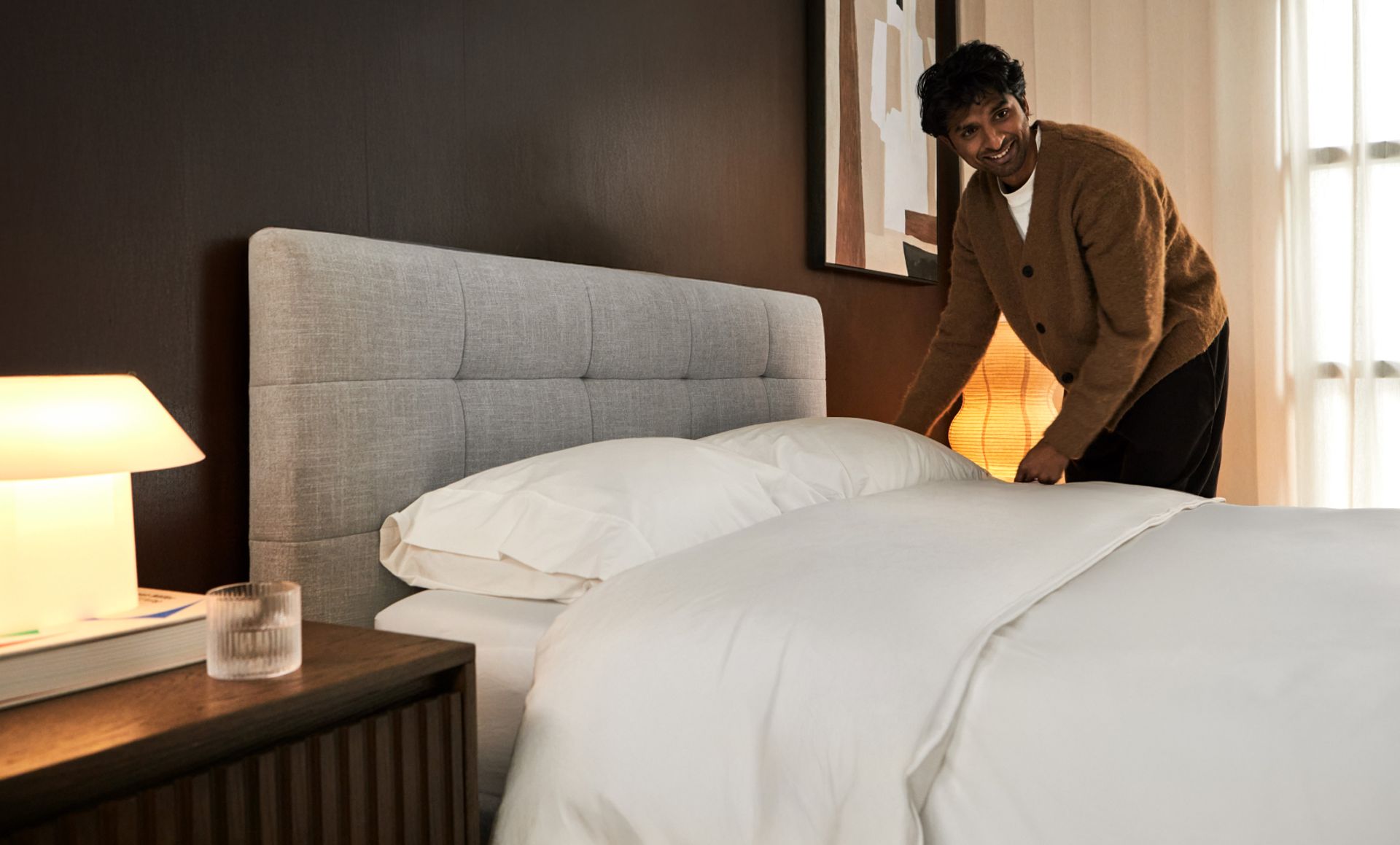 Tufted upholstered bed frame in ash grey equipped with midnight nave bedding.