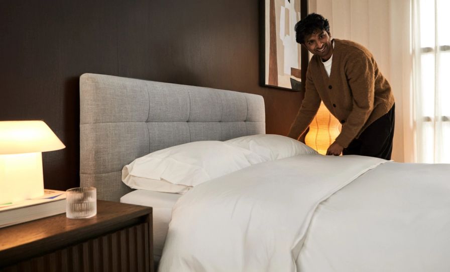 Tufted upholstered bed frame in ash grey equipped with midnight nave bedding.