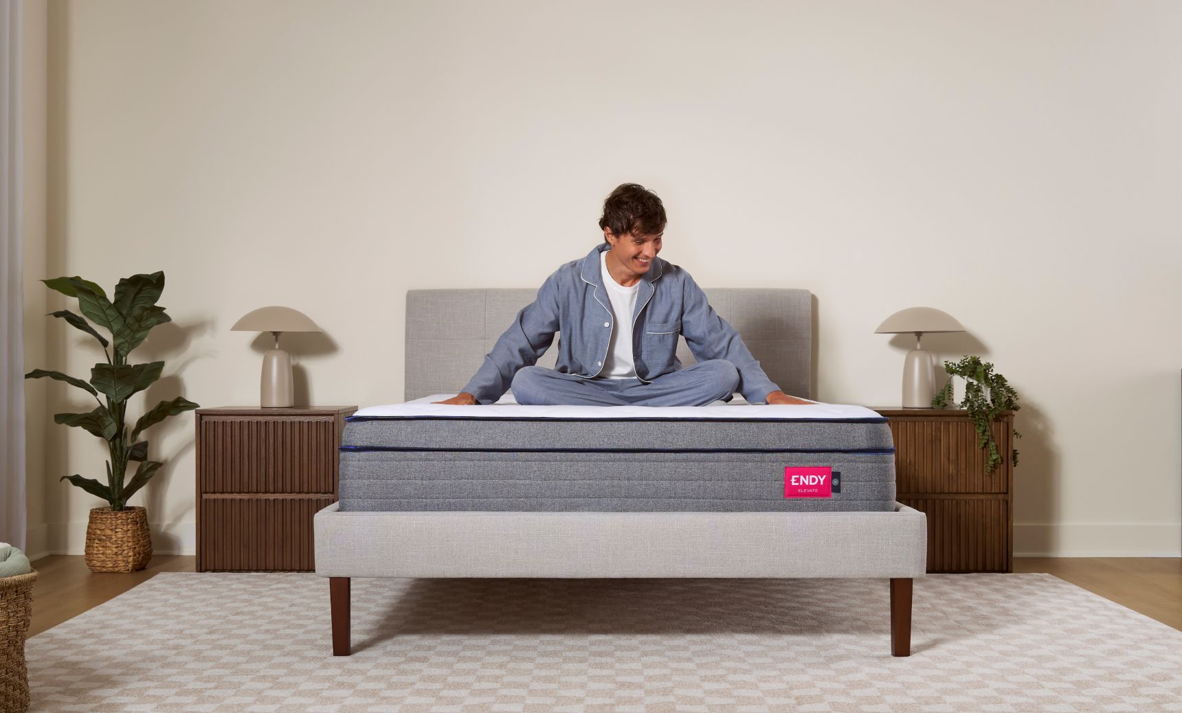 Man sitting cross-legged on top of an Endy Elevate Hybrid mattress