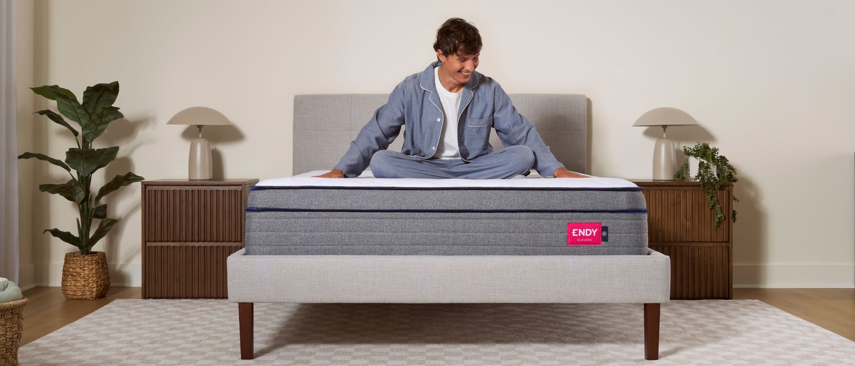 Man sitting cross-legged on top of an Endy Elevate Hybrid mattress