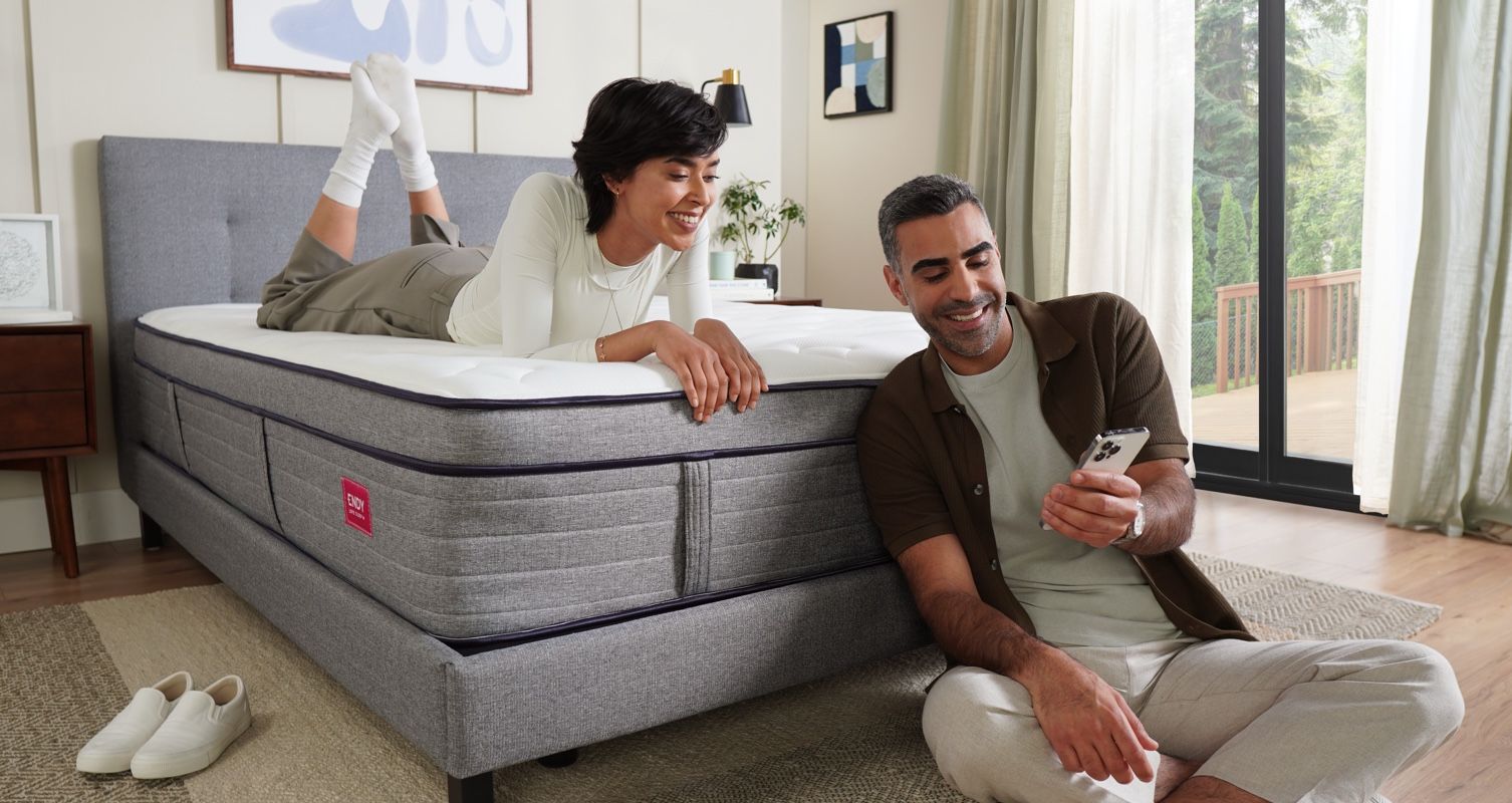 a person on the endy mattress looking at phone held up by another person on the floor