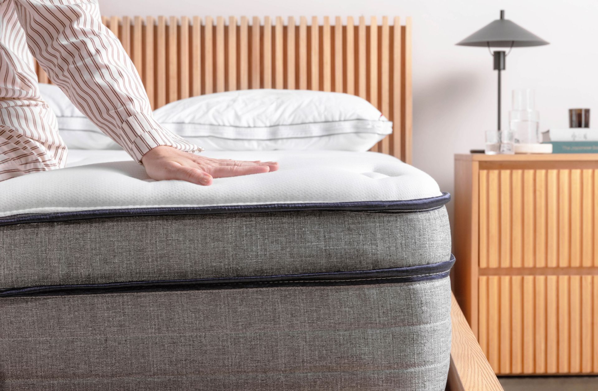 Person sitting on the edge of the Endy Hybrid Mattress to demonstrate construction.
