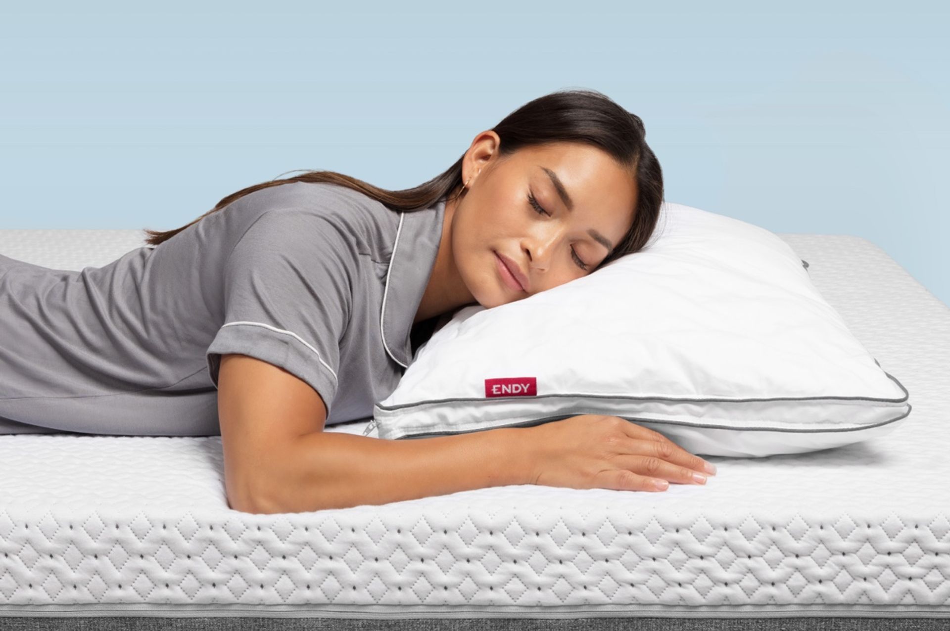 Woman lying on her stomach on an Endy Mattress with a pillow under her head