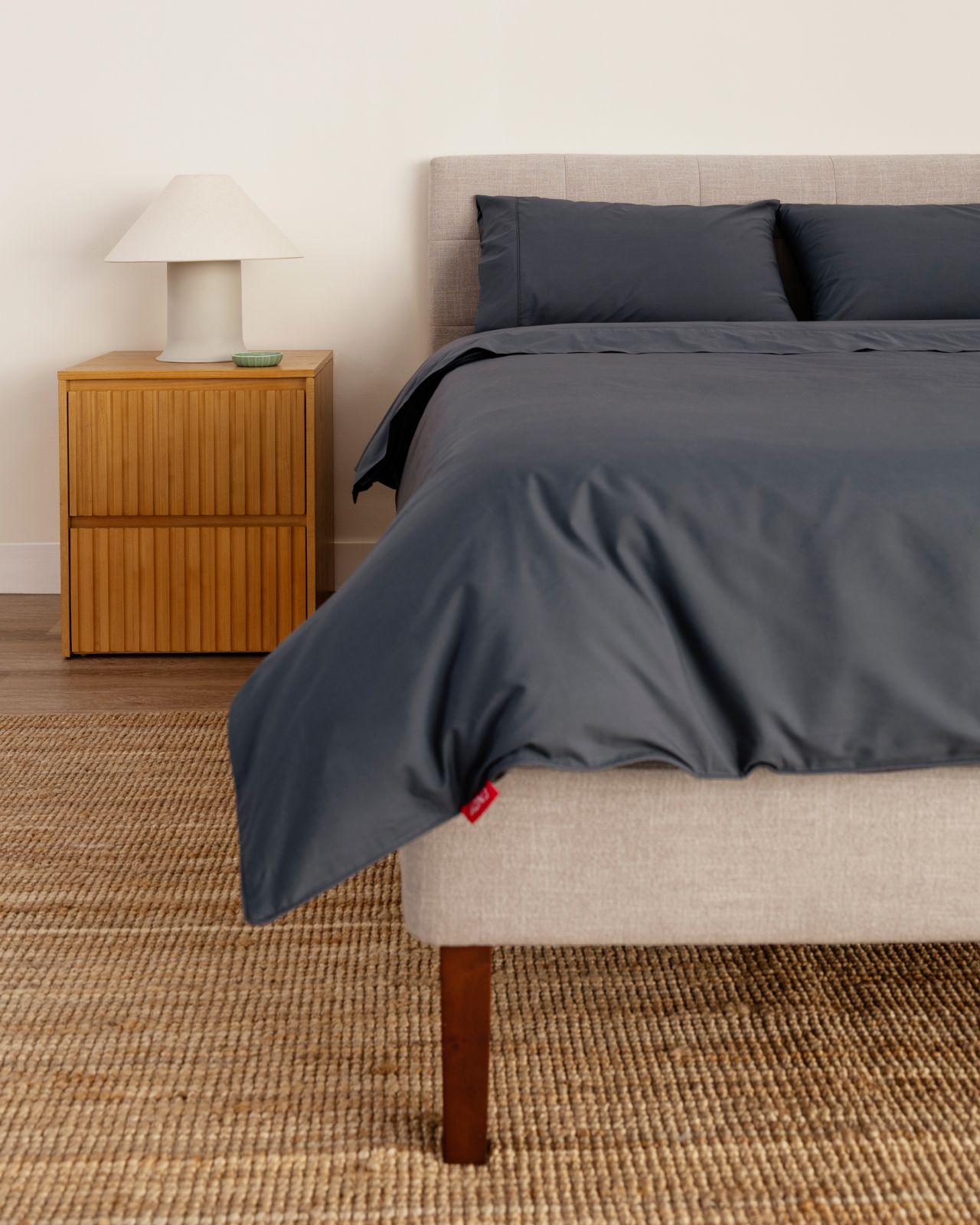 Bedroom featuring the tufted upholstered bed frame in ash grey with the wooden nightstand.