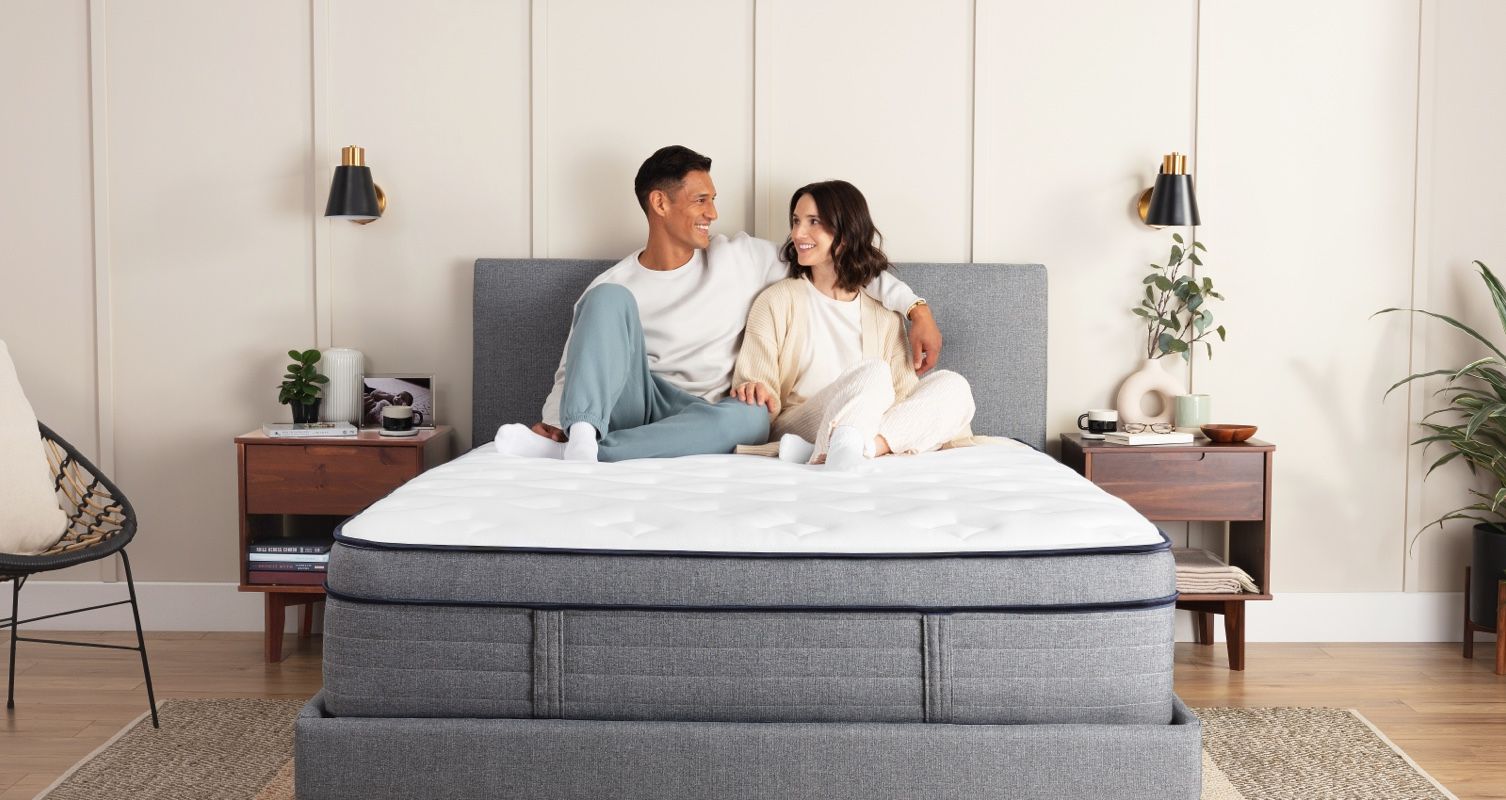 A man and woman sitting on an Endy Hybrid Mattress.